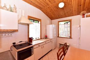 a kitchen with white appliances and a wooden ceiling at "Senoji sodyba" in Anykščiai