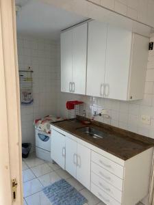 uma cozinha com armários brancos e um lavatório em Apartamento Giovanni Gronchi em São Paulo