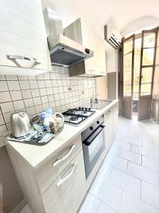 una cucina con mobili bianchi e un forno a piano cottura di Pigna Tommy House a Sanremo