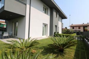 Biały dom z dwoma palmami na dziedzińcu w obiekcie Marali Lake Apartments w mieście Desenzano del Garda
