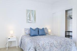 a white bedroom with a bed with blue pillows at Wynwood Modern 1 Bedroom in Miami