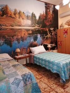 two beds in a room with a painting of a lake at B&b Fabra Casa Mia e non solo in Falvaterra