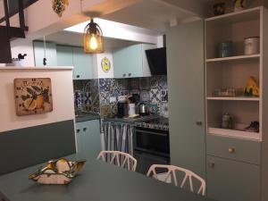 une cuisine avec des armoires bleues et une table et des chaises dans l'établissement Charmant Studio avec Mezzanine, Climatisé, au Cœur de Menton, Proche Plages et Commerces - FR-1-196-300, à Menton