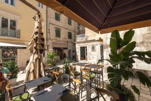 een patio met tafels en stoelen en een parasol bij Dolce Vita Apartments in Split