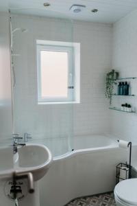 een witte badkamer met een bad en een wastafel bij Stylish Belfast City Centre 2 Bedroom Apt Free Parking in Belfast