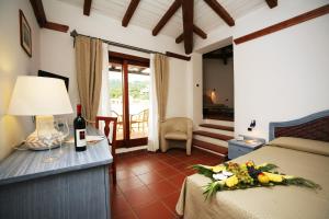 a hotel room with a bed and a table with a bottle of wine at Hotel Palumbalza Porto Rotondo in Porto Rotondo