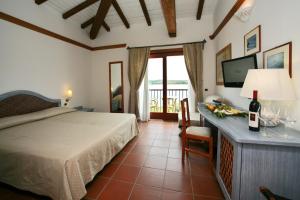 een slaapkamer met een bed en een tafel met een fles wijn bij Hotel Palumbalza Porto Rotondo in Porto Rotondo