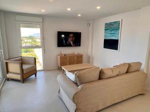 a living room with a couch and a television on the wall at Penthouse panoramic sea view in Oliva