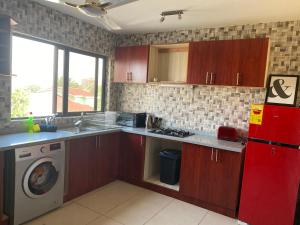 eine Küche mit einem roten Kühlschrank und einer Waschmaschine in der Unterkunft Newly Built 2 bedroom En-suite Apt. in Accra