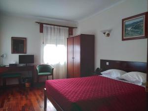 a bedroom with a red bed with a desk and a computer at Hotel Trindade Coelho in Mogadouro