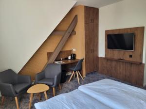 Schlafzimmer mit einem Bett, einem Schreibtisch und einem TV in der Unterkunft Pension zum Kleistpark in Frankfurt (Oder)