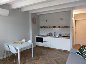 HomeThirtyFour في فيرونا: مطبخ أبيض مع طاولة بيضاء وكراسي