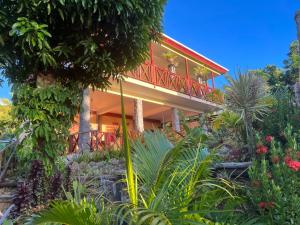 a house with a red balcony and some plants at Mabrika Resort Dominica in Guillet