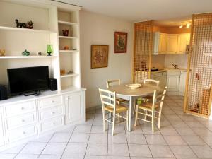 eine Küche mit einem Tisch und Stühlen sowie einem TV in der Unterkunft Les Dunes - A 150m de la Grande Plage in Les Sables-dʼOlonne