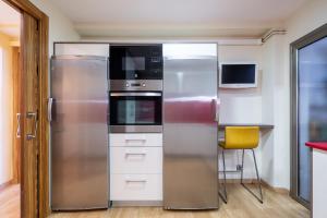 een roestvrijstalen koelkast in een keuken met een gele stoel bij Hauzify I Apartament Sant Roc in L'Ametlla de Mar
