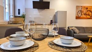 einen Holztisch mit Tellern und Weingläsern darauf in der Unterkunft Magnifique appartement rénové plein centre-ville in Marmande