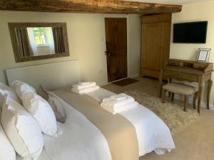 a bedroom with a bed with white pillows and a desk at Church Farm in Thurlton