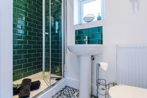 a bathroom with a sink and a shower with green tiles at Spacious 4-bed house in Crewe by 53 Degrees Property, ideal for Business & Contractors, Great Location - Sleeps 8 in Crewe