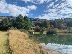 a view of a lake with a house in the background at Brackenburn Trout and Trail Retreat in Elandskop