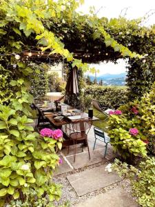 um jardim com uma mesa e cadeiras sob uma pérgola em Sunset Feel House em Blevio