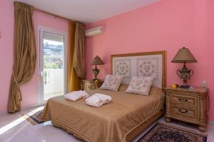 a bedroom with pink walls and a bed with two pillows at Vergis Epavlis in Agios Myronas