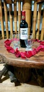 Una botella de vino y dos copas en una mesa de madera. en Casa Pampa, en San Agustín