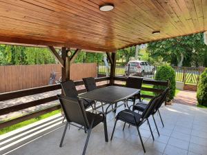 a patio with a table and chairs under a wooden pergola at Napfény Vendégház in Vonyarcvashegy