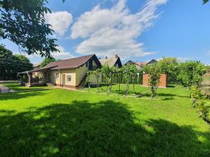 a house with a yard with green grass and trees at Napfény Vendégház in Vonyarcvashegy
