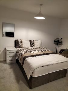 a bedroom with a large bed with a night stand and a lamp at NHYL HOMES in Wibsey