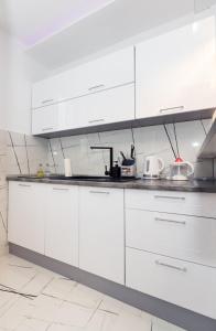 eine weiße Küche mit weißen Schränken und Geräten in der Unterkunft Foča Apartman STORY LUX in Foča + 22 Fotos