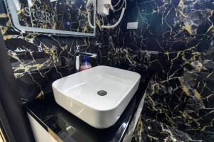 ein Badezimmer mit einem weißen Waschbecken in einer Marmorwand in der Unterkunft Foča Apartman STORY LUX in Foča