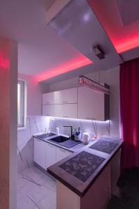 Eine Küche mit weißen Schränken und roter Beleuchtung in der Unterkunft Foča Apartman STORY LUX in Foča
