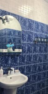 een blauw betegelde badkamer met een wastafel en een spiegel bij Къща за гости Шарон in Petrich
