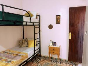 a bedroom with two bunk beds and a night stand at Vibe Surf Morocco in Agadir