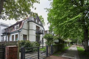 Biały dom z płotem przed nim w obiekcie Apartamenty Świnoujście - Villa Stil 1 w Świnoujściu