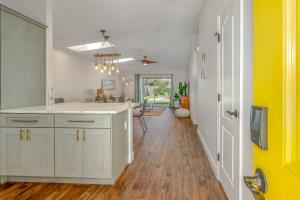 a kitchen with white cabinets and a yellow wall at Unique Balinese Home with Fire Pit and Private Fenced Yard! 30 Seconds to the Sand! in New Smyrna Beach