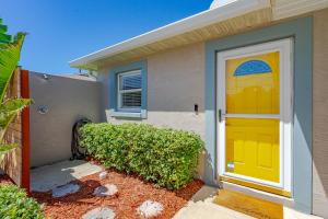 una casa con una puerta amarilla delante de ella en Unique Balinese Home with Fire Pit and Private Fenced Yard! 30 Seconds to the Sand! en New Smyrna Beach