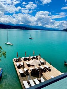 eine Anlegestelle mit Stühlen und Sonnenschirmen auf dem Wasser in der Unterkunft Hotel Schloss Leonstain in Pörtschach am Wörthersee