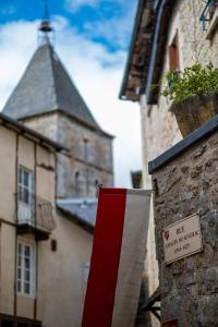 um sinal no lado de um edifício com uma torre em La Suite des Consuls em Sévérac d' Aveyron