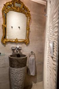 uma casa de banho com um espelho e um lavatório em La Suite des Consuls em Sévérac d' Aveyron