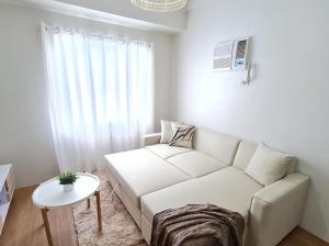 sala de estar con sofá blanco y mesa en Lovely 2- BR Condo (Fully Air-conditioned w/ Wifi), en Cagayan de Oro