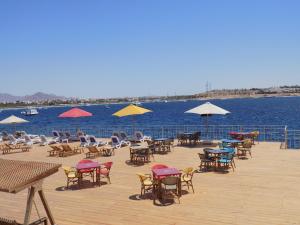 una terraza con sillas, mesas y sombrillas en el agua en Jewel Sharm El Sheikh Hotel en Sharm El Sheikh