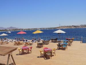 a deck with chairs and tables and umbrellas on the water at Jewel Sharm El Sheikh Hotel in Sharm El Sheikh