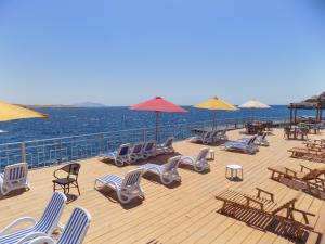 een terras met ligstoelen en parasols en de oceaan bij Jewel Sharm El Sheikh Hotel in Sharm El Sheikh
