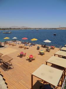 Jewel Sharm El Sheikh Hotel في شرم الشيخ: سطح خشبي مع كراسي ومظلات على الماء