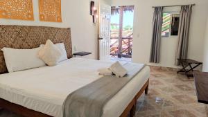 a white bed sitting in a bedroom next to a window at Tropical Rooms Holbox in Holbox Island