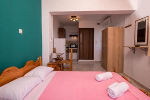 a bedroom with a large bed with a pink blanket at Elena Studios in Athani