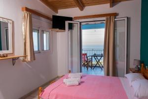 Dormitorio con cama rosa y vistas al océano en Elena Studios, en Athani