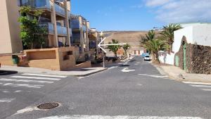 una calle urbana vacía con edificios y palmeras en Residencial Esquinzo 2, en Playa de Jandía