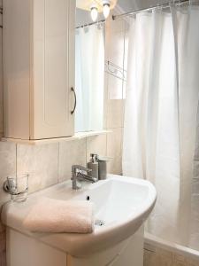 een badkamer met een witte wastafel en een douche bij URBAN APARTMENT in Lefkada